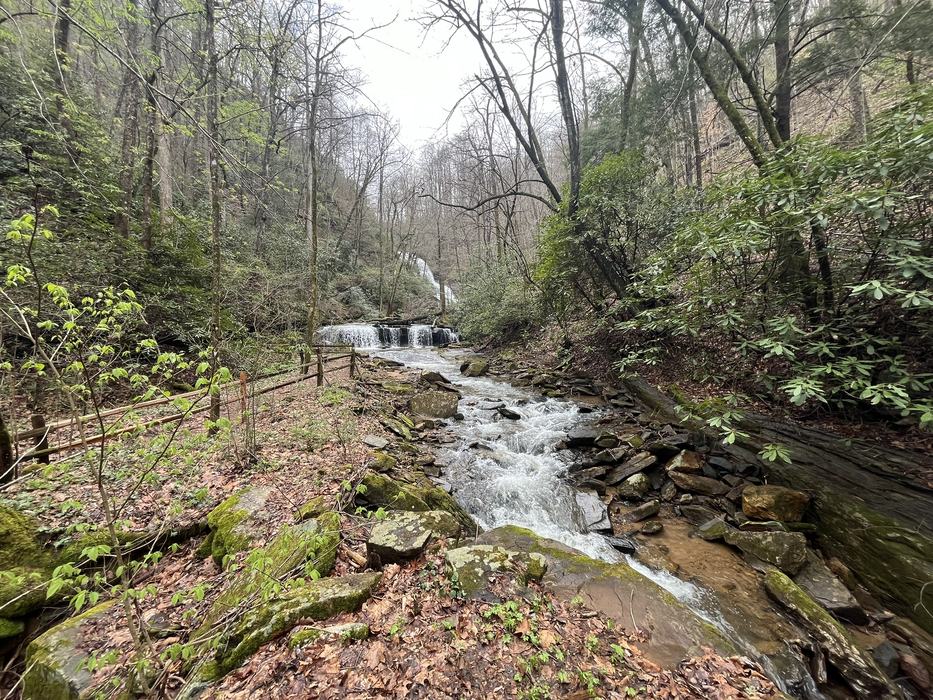 A stream flows down from a waterfall in the distance.