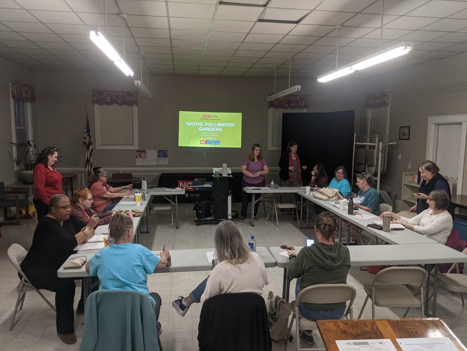 Workshop attendees around U-shaped tables; projector slide: NATIVE POLLINATOR GARDENS