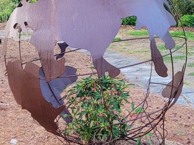 metal earth sculpture with green plant vine inside