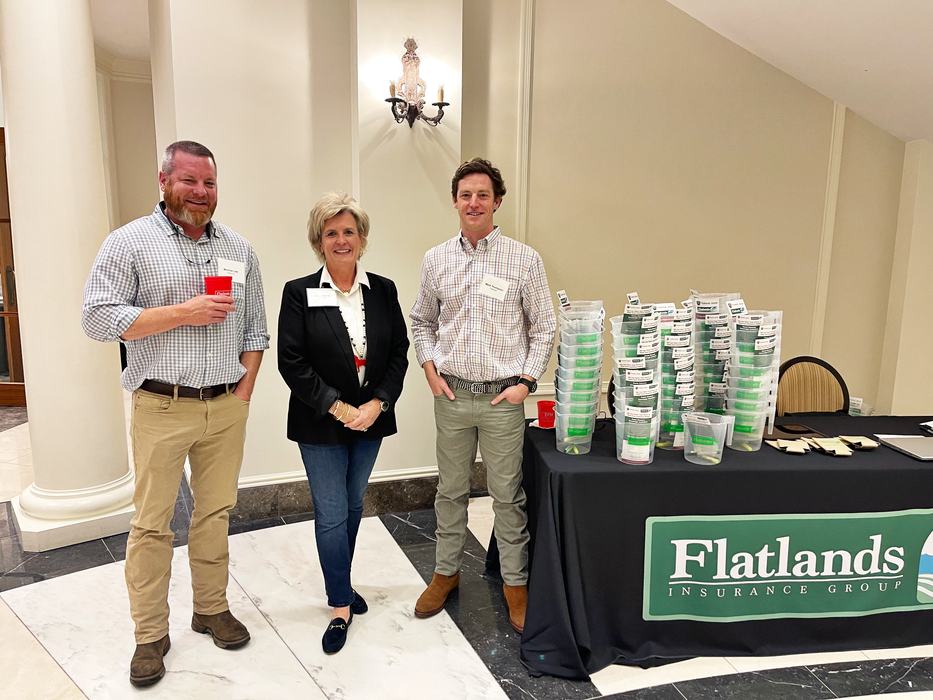 Three people stand beside a flatlands table.