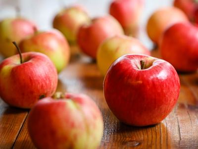 Red apples on a wooden table, single apple in sharp focus at front