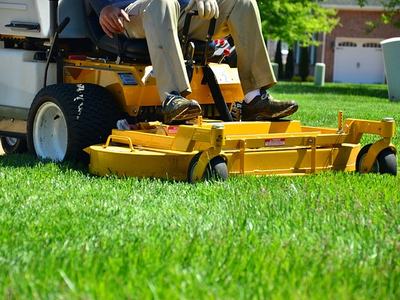 person mowing lawn on yellow mower