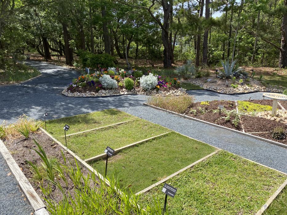 Garden display with labeled turf plots, gravel paths, flower beds; sign reads "GROUND COVERS"