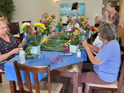 Group of people arranging colorful flowers at a table covered with a blue cloth