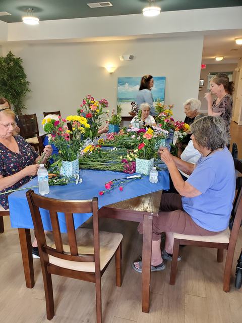 Group of people arranging colorful flowers at a table covered with a blue cloth