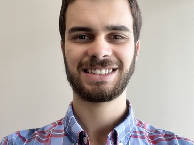 Young man wearing blue plaid button-down shirt, facing the camera