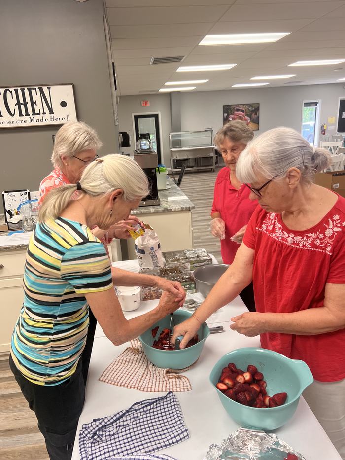 Women process strawberries together.