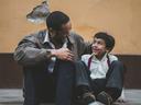 father and son sitting on sidewalk