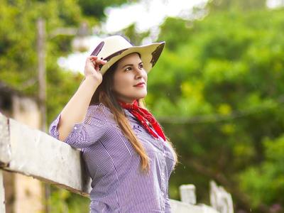 woman wearing a cowboy hat leaning on a fence