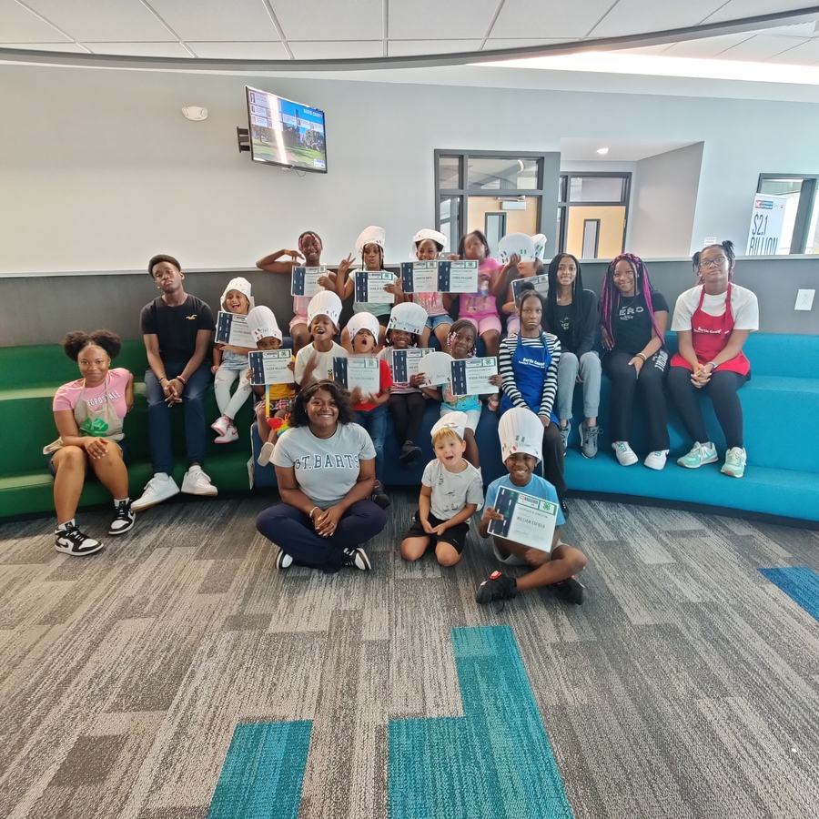 Kids wearing chefs hats pose together.