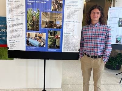Alexander Kaufhold standing with his internship presentation poster.