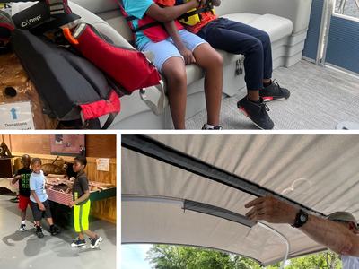 Two children wearing life jackets hugging on a pontoon boat bench by a river