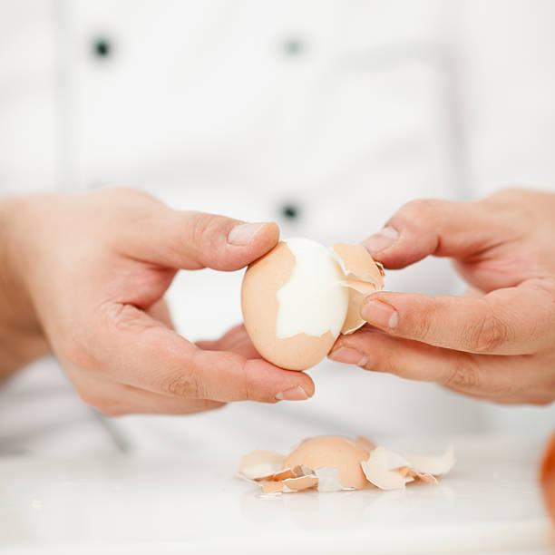 Chef peeling boiled egg in domestic kitchen / close-up shot / focus on egg