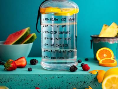 water bottle marked with motivation to hydrate and surrounded by various fruits on a blue background