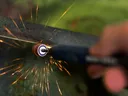 Sharpening lawn mower blade with rotary grinder.