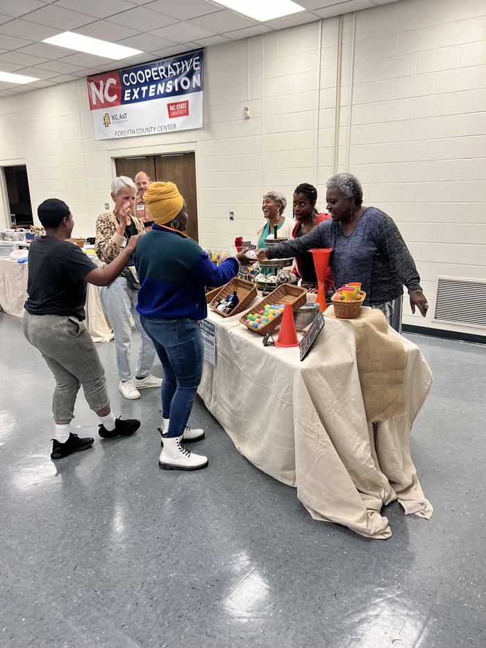 People at NC Cooperative Extension table exchanging items at community event