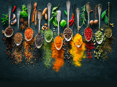 spoons line up on black background full of various herbs and spices