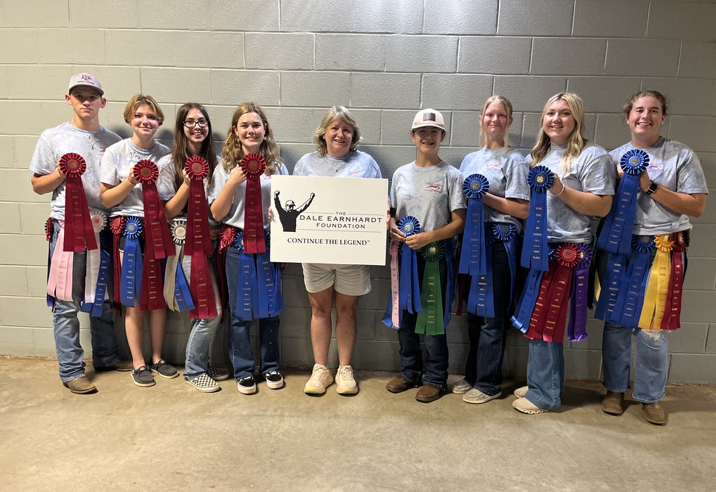 Group of youths holding ribbons and a sign: "The Dale Earnhardt Foundation — Continue the Legend"