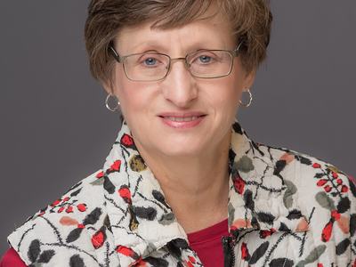 Portrait of a smiling woman in a white vest.
