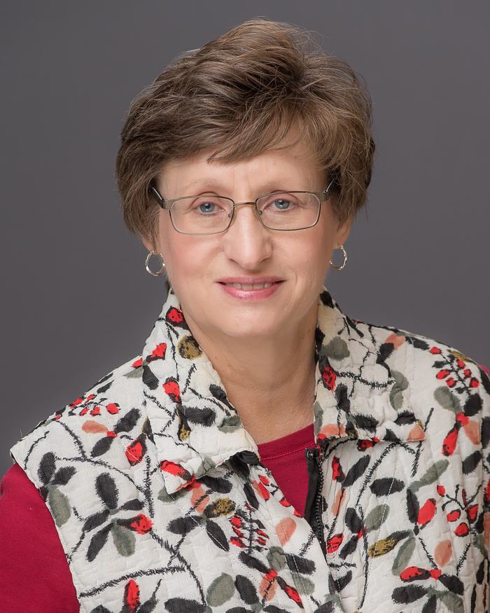 Portrait of a smiling woman in a white vest.