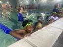 Group of children in goggles holding the pool edge during a swim lesson