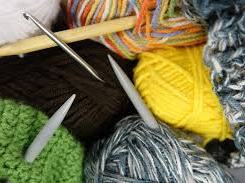 Multiple colorful yarn balls with knitting needles and a green partially knit piece