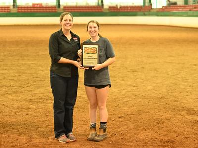 Two people standing in an arena holding a plaque reading "Senior Sportsmanship Award"