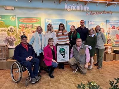 Sampson Ag Advisory Board with new farm sign (2024): Kent Fann, Jennifer Daniels, Nelson Powell (front row); Wendy Dorman, Anita Lane, Morgan Moore, Melanie Harris, Henry Faison, Susan Heath, Eileen Coite (back row)