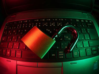 Unlocked padlock lying on a laptop keyboard illuminated red and green
