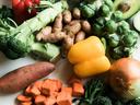 Assorted fresh vegetables: yellow and red bell peppers, brussels sprouts, avocado, sweet potato cubes