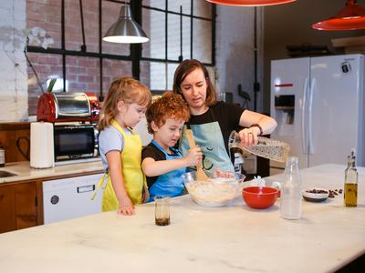 mother and two children mixing items in glass bowl at the counter of a kitchen