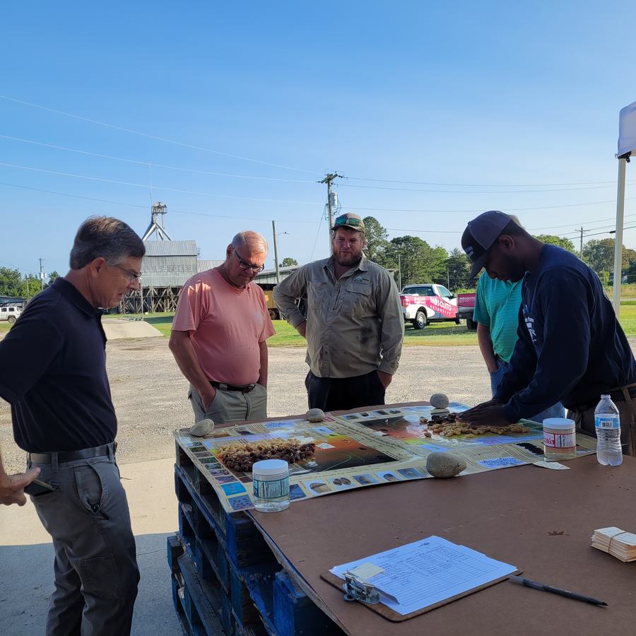 Men stand together at a table to look at a pod maturity chart.