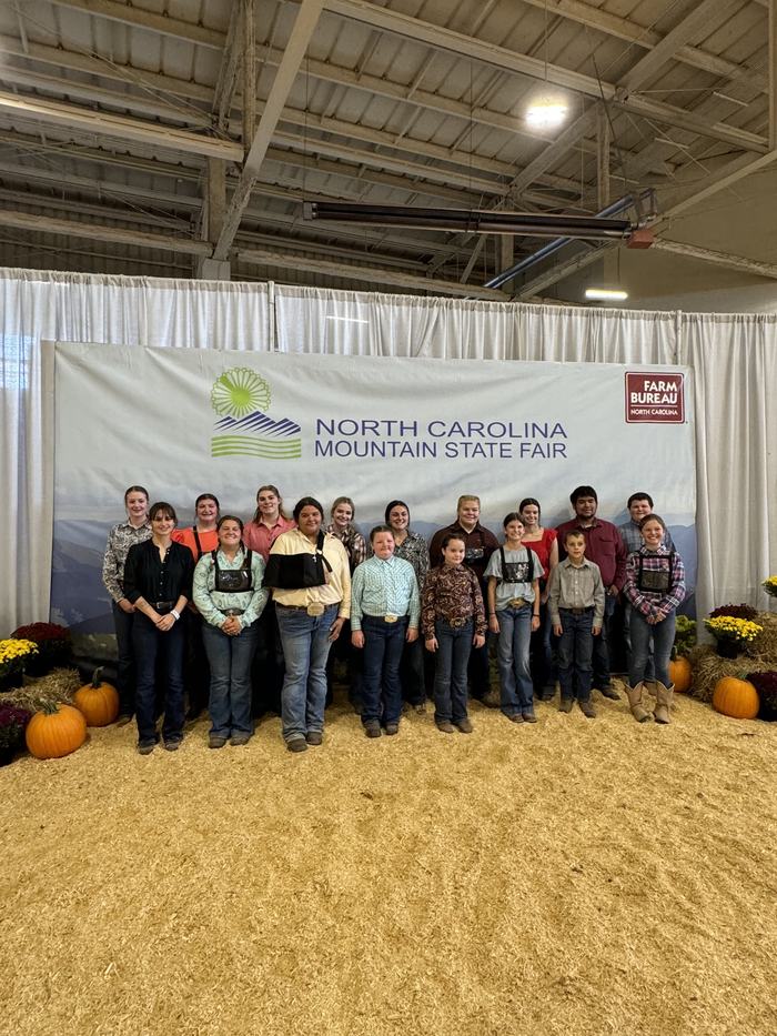Group of people standing in front of a banner reading "North Carolina Mountain State Fair."