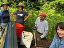 Four people gardening at a truck bed with shovel and buckets; one shirt reads "GRP".