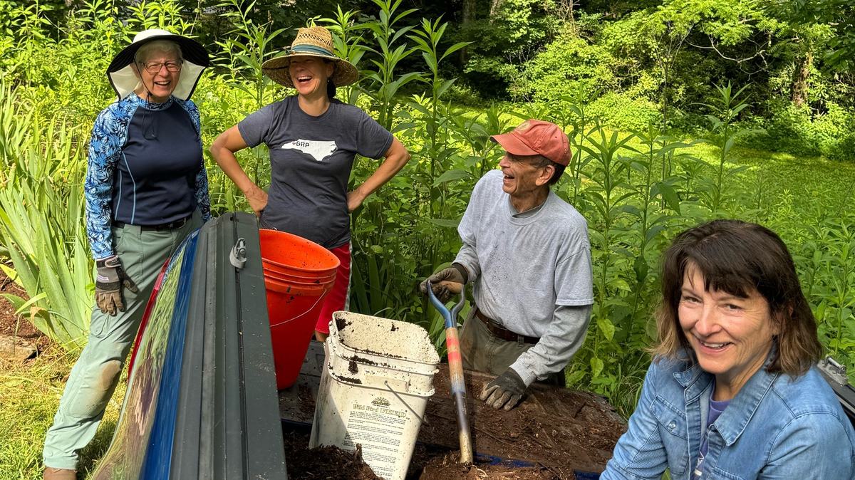 Four people gardening at a truck bed with shovel and buckets; one shirt reads "GRP".