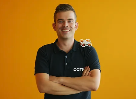 A man stands with a drone on his shoulder.