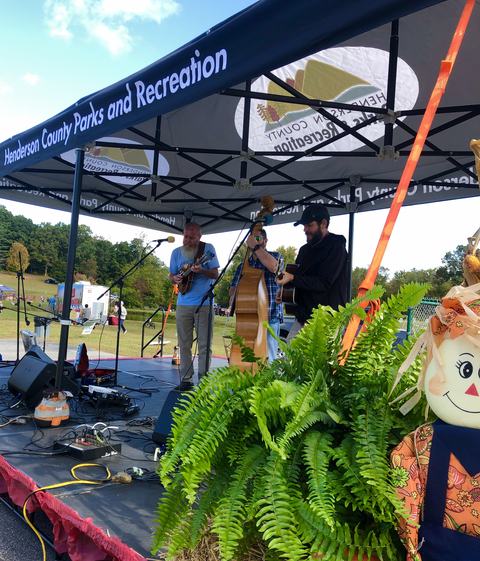 Musicians play on a black stage, under a canopy.