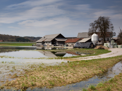 Farm buildings and silo beside a flooded field with water reflecting the barns