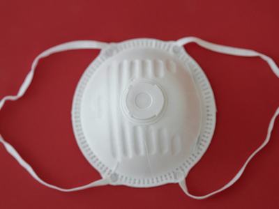 White N95 respirator mask with exhalation valve and elastic straps on red background