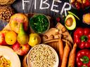 Foods rich in fiber as rye galette , wheat bran, beans , almonds, seed, pears, plum bananas, cranberry, raspberries, pistachios, red pepper kiwi walnuts melon celery carrot Wooden table as background