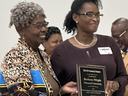 Two women holding a plaque reading "Barbara Wright" during an award presentation.