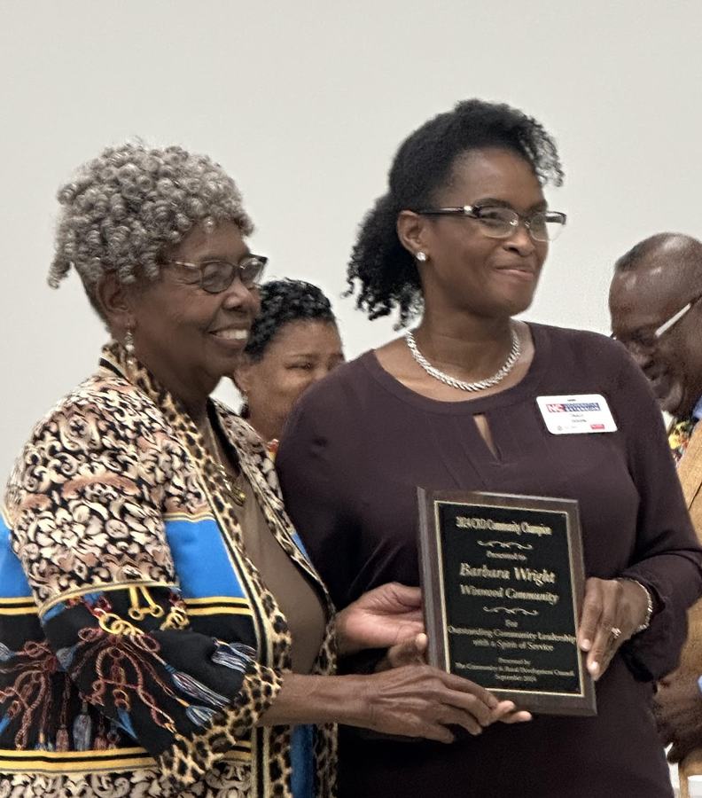 Two women holding a plaque reading "Barbara Wright" during an award presentation.