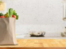 Brown paper grocery bag with fresh vegetables on a kitchen countertop