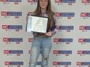 Teen girl holding framed horse drawing with blue ribbon in front of NC Cooperative Extension backdrop