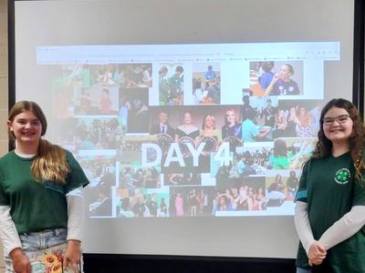 Two girls pose with a presentation.