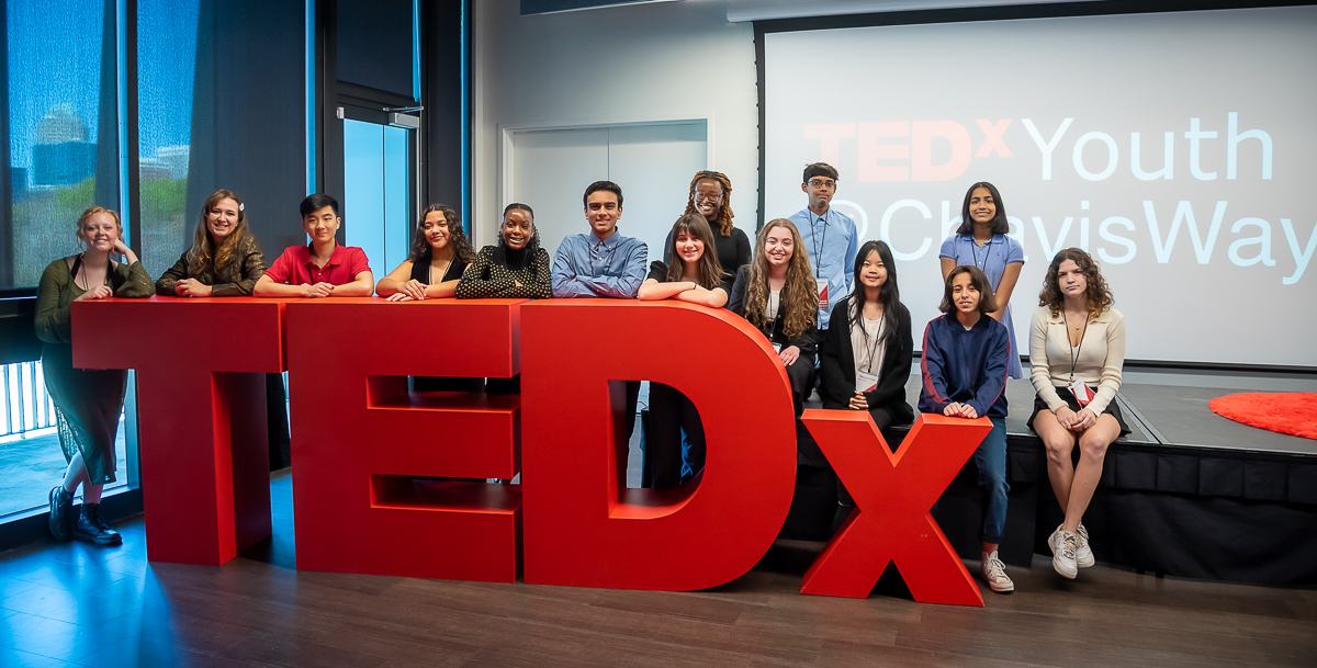 Kids standing behind TEDx letters