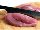 Raw pork tenderloin slices on wooden cutting board with a chef's knife