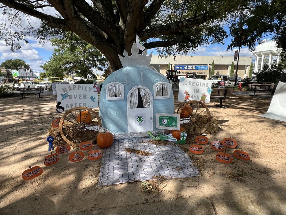 Blue carriage display with pumpkins and signs "HAPPILY EVER AFTER... BEGINS IN 4‑H"