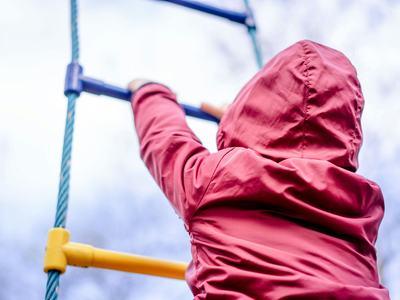 image of child in red coat climbing rope ladder