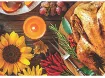 Roasted turkey at center surrounded by pumpkins, gourds, sunflowers, and candles.